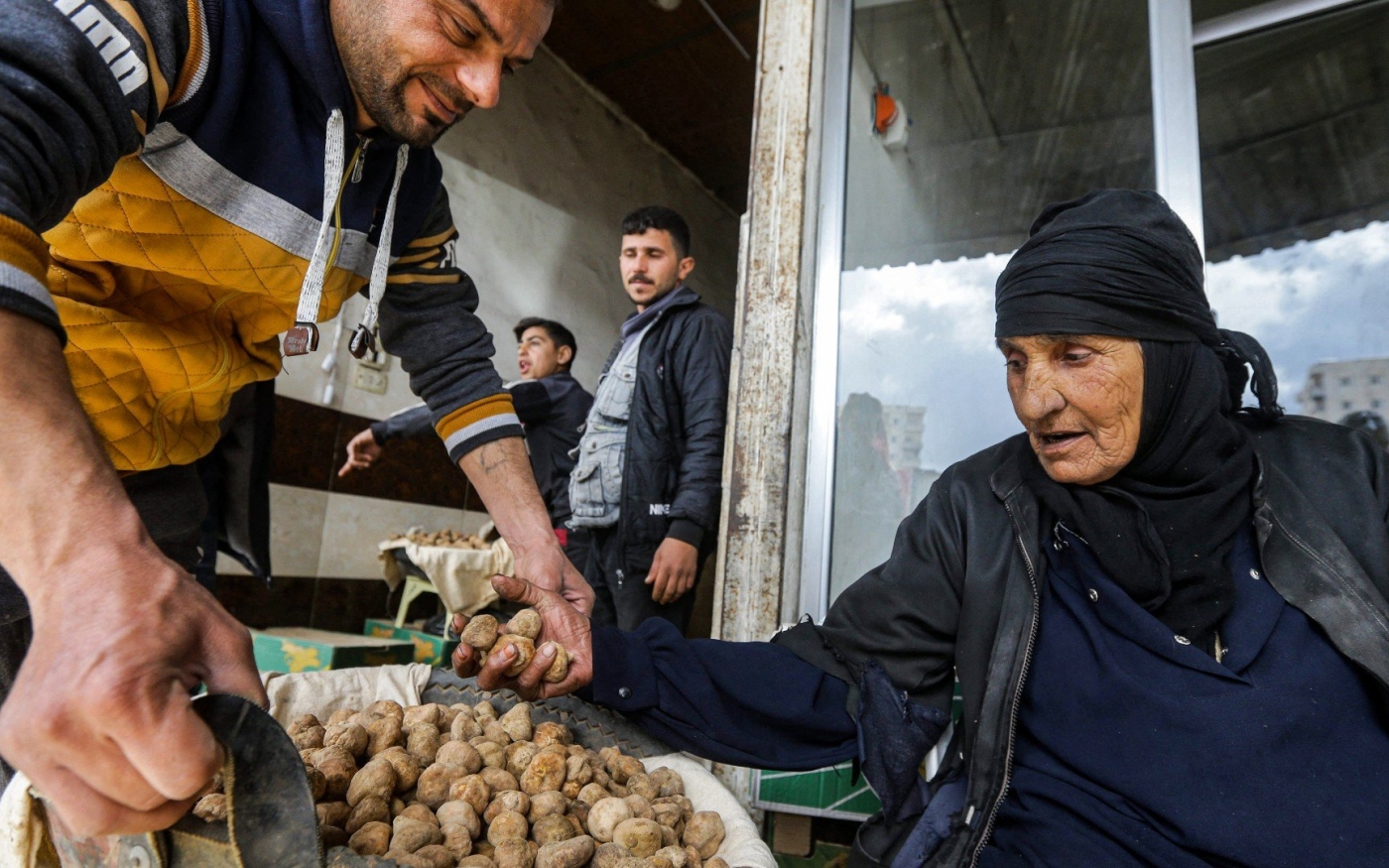 Un commerçant aide une femme à trier des truffes du désert sur un marché de la ville de Hama, dans le centre-ouest de la Syrie, le 6 mars (AFP)