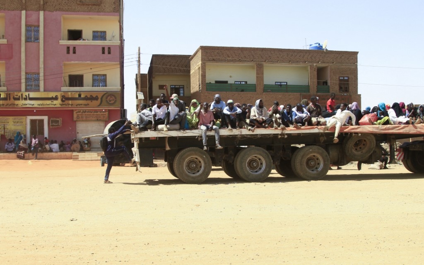 Des personnes fuyant des combats de rue entre les forces de deux généraux soudanais rivaux, sont transportées à l’arrière d’un camion dans la partie sud de Khartoum, le 21 avril 2023 (AFP)