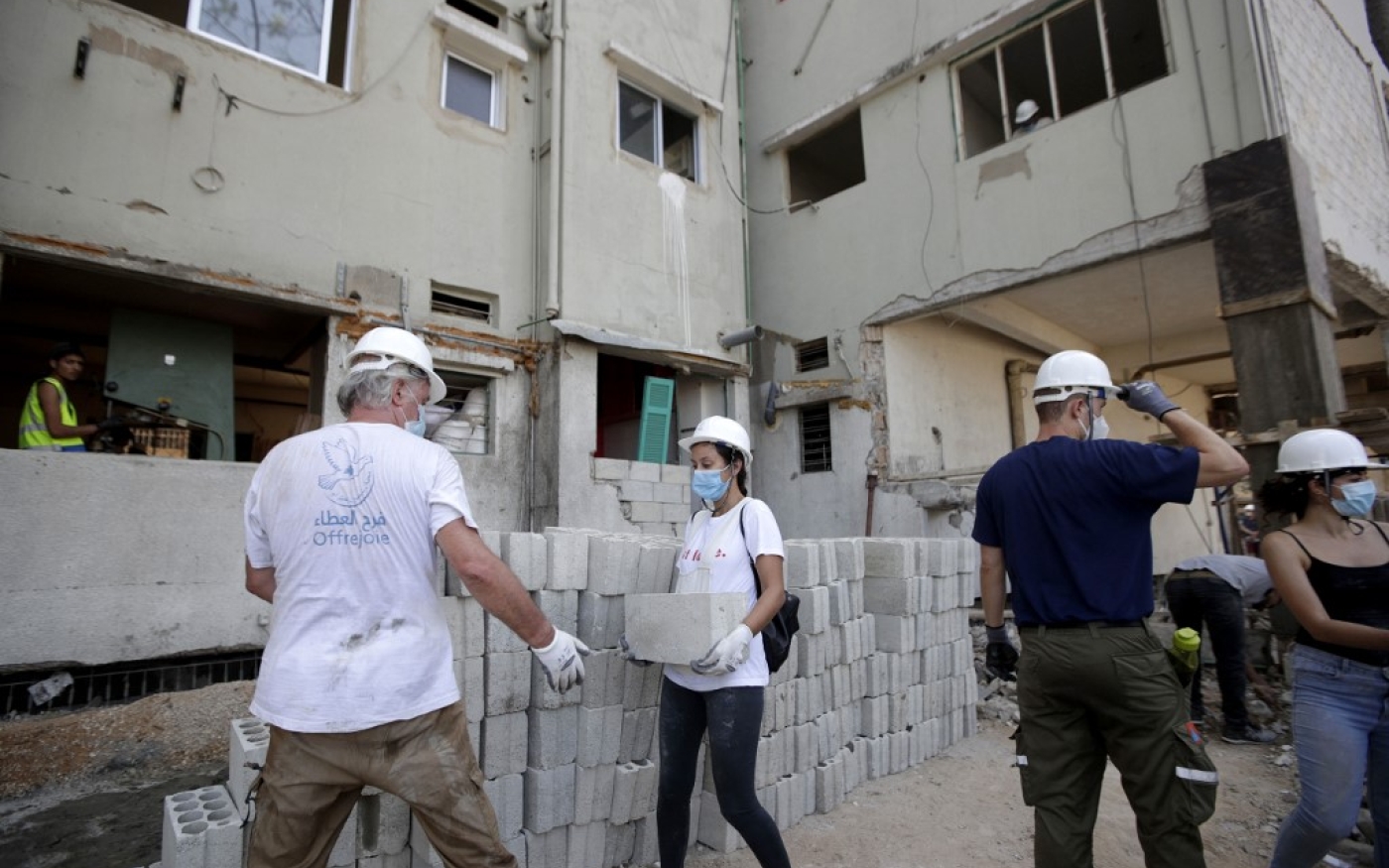 Des volontaires de l’ONG libanaise AGBU (Armenian General Benevolent Union) aident aux travaux de restauration d’un immeuble endommagé par l’explosion du 4 août 2010 dans le port de Beyrouth (AFP)