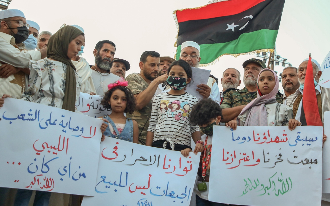 Des manifestants libyens brandissent des pancartes et des drapeaux libyens lors d’un rassemblement sur la place des Martyrs de Tripoli pour protester contre la détérioration de la situation politique et sécuritaire et des conditions de vie, le 2 octobre (AFP)