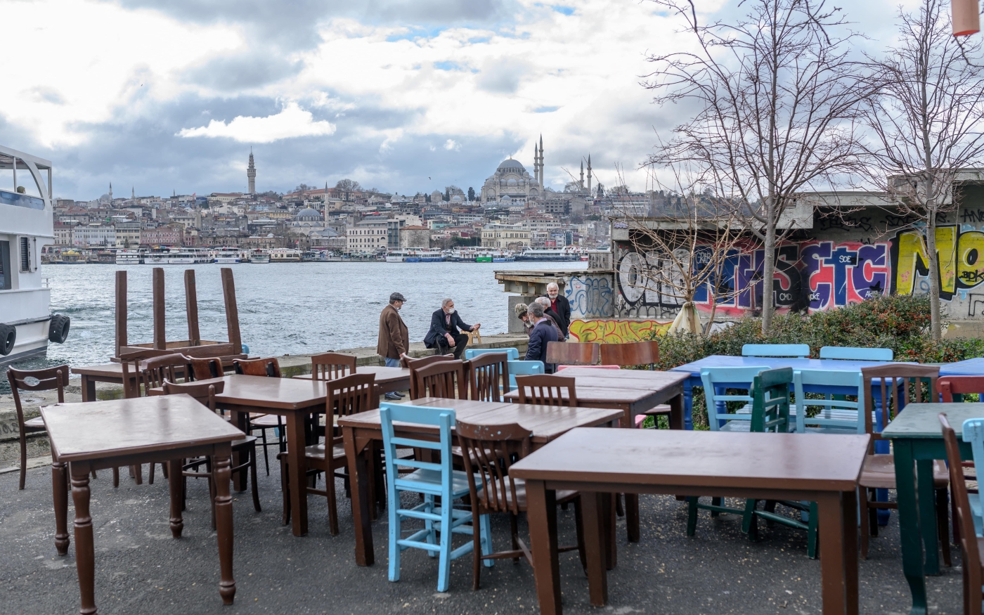 People talk by seaside by a restaurant at Karakoy, Istanbul, on 2 March 2021, before restrictions were again placed on dining out. (Bulent Kilic/AFP)