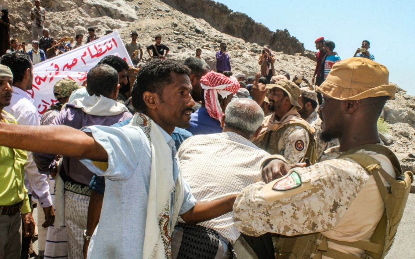 Un manifestant se dispute avec un membre des forces de sécurité de la coalition soutenue par l'Arabie saoudite devant le siège du gouvernement yéménite à Aden, au sud du pays, le 16 mars 2021 (AFP)