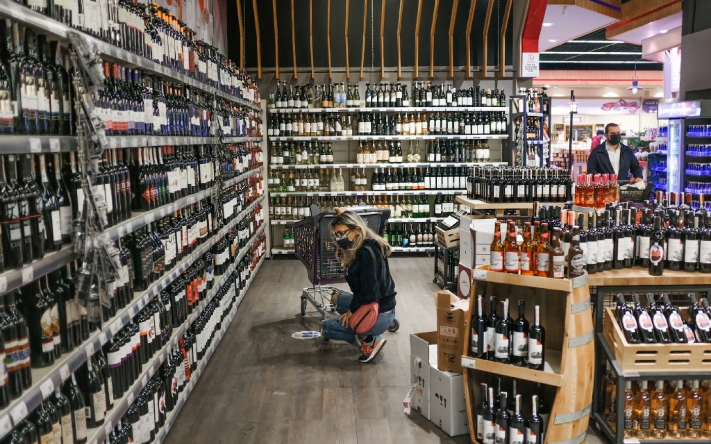 Une cliente choisit ses boissons au rayon alcool d’un supermarché juste avant l’interdiction de vente d’alcool annoncée par le gouvernement (AFP)