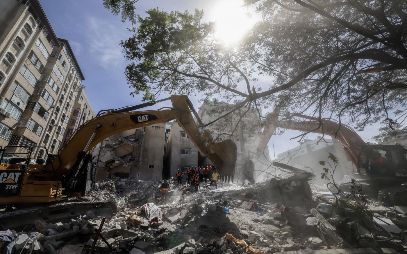 Une pelleteuse dégage les décombres d’un bâtiment détruit dans le quartier résidentiel al-Rimal de Gaza après une frappe aérienne israélienne, le 16 mai 2021 (AFP)