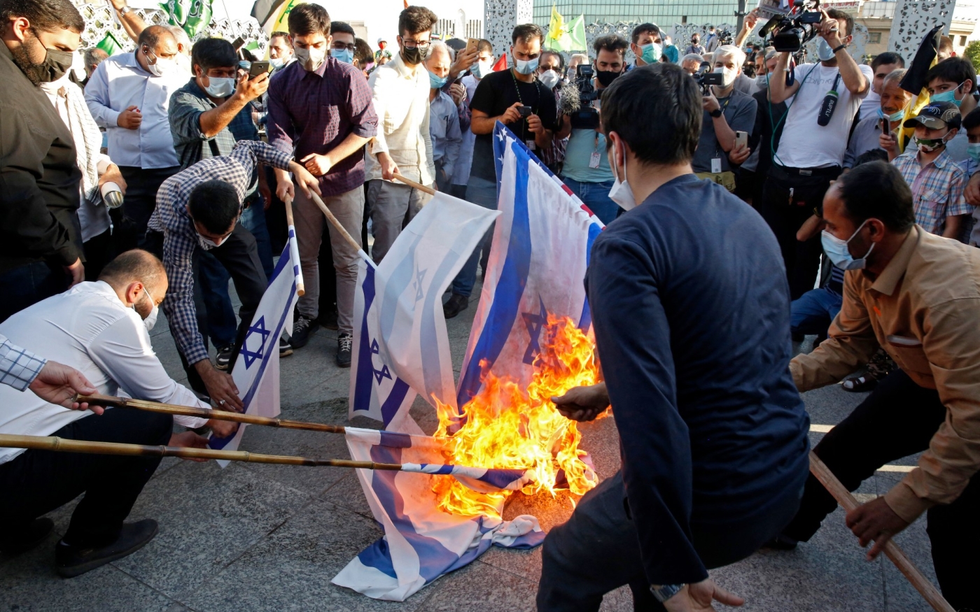 Des Iraniens brûlent des drapeaux israéliens lors d’un défilé condamnant les frappes israéliennes sur la bande de Gaza, sur la place de la Palestine dans la capitale Téhéran, le 19 mai dernier (AFP)