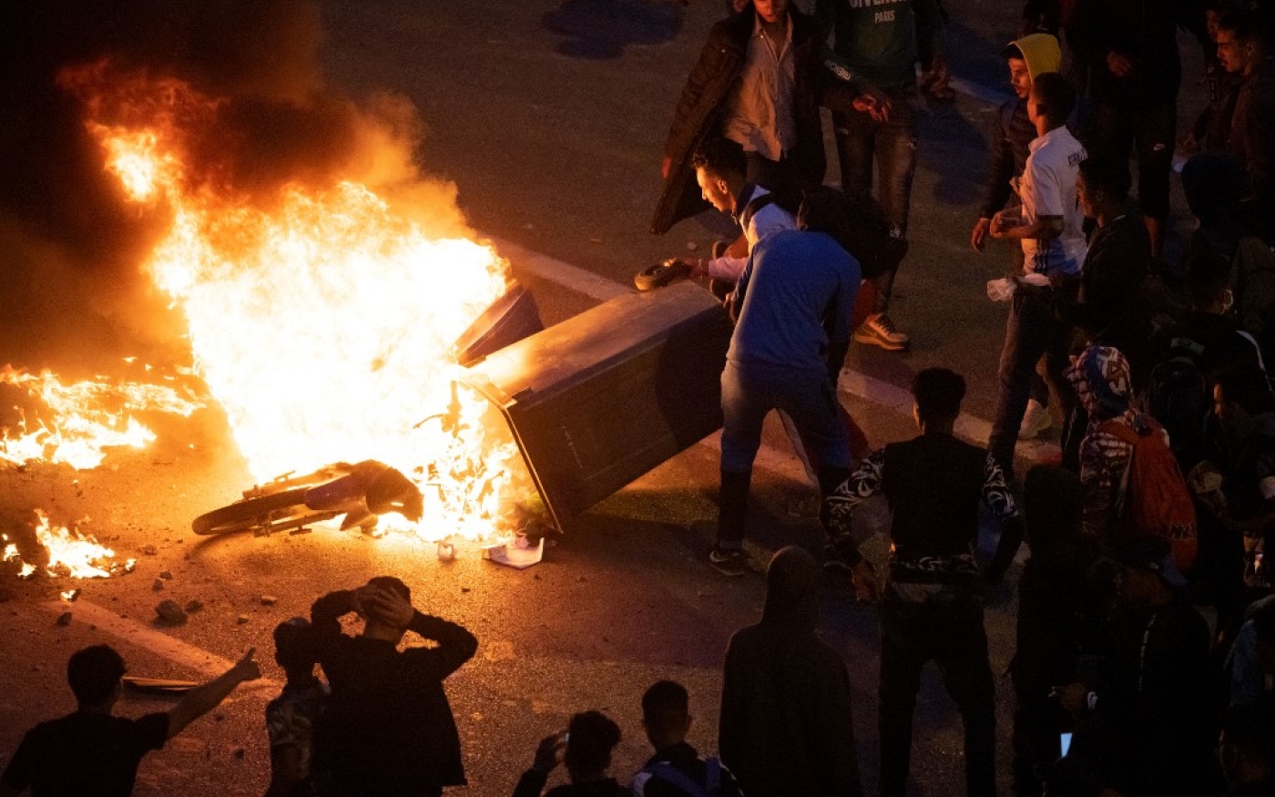 Des jeunes incendient une moto et une poubelle lors d’affrontements avec la police marocaine pour protester contre l’interdiction de franchir la frontière, à Fnideq, le 19 mai 2021 (Fadel Senna/AFP)