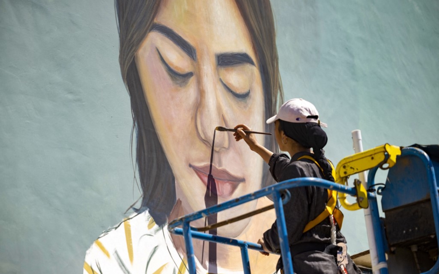 L’artiste Imane Droby réalise le portrait d’une brodeuse sur la façade d’une école publique à Rabat, le 20 septembre 2021 (AFP/Fadel Senna)