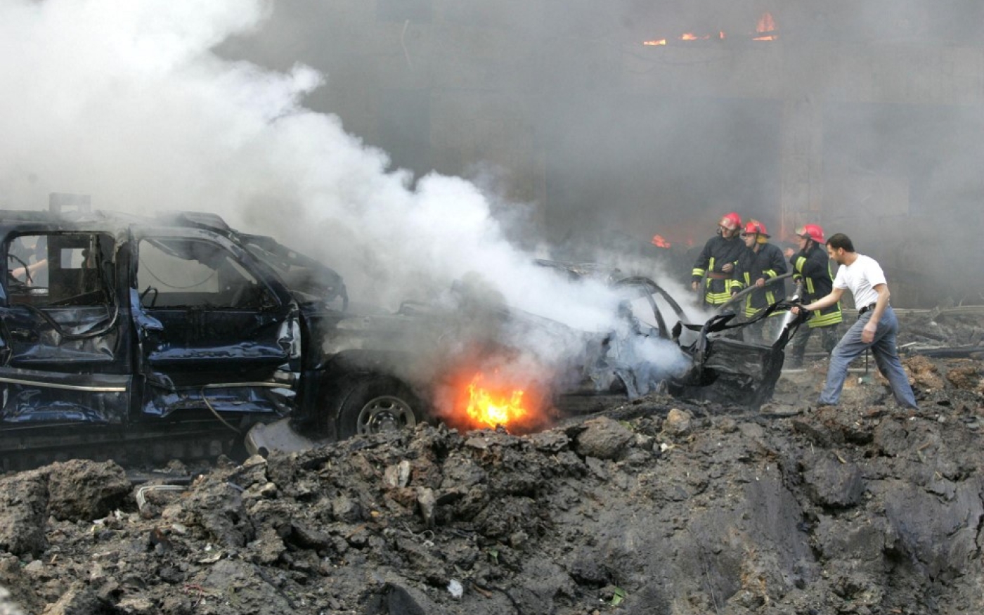 Des pompiers tentent d’éteindre le feu dans le convoi du Premier ministre Rafiq Hariri, décimé par une explosion, le 14 février 2005 à Beyrouth (AFP/Joseph Barrak)