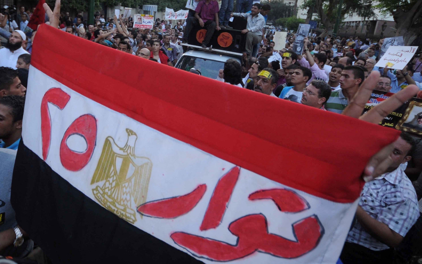Un manifestant égyptien brandit son drapeau national avec le slogan « Révolutionnaires du 25 », en référence à la révolution (AFP)