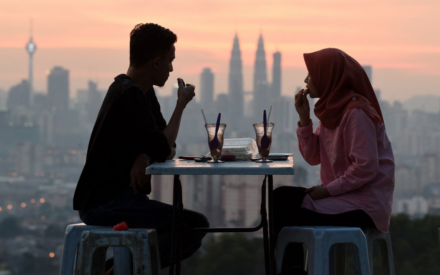 Des musulmans malaisiens rompent leur jeûne pendant le mois sacré du Ramadan avec en toile de fond de la ligne d’horizon de Kuala Lumpur (AFP/Manan Vatsyayana)