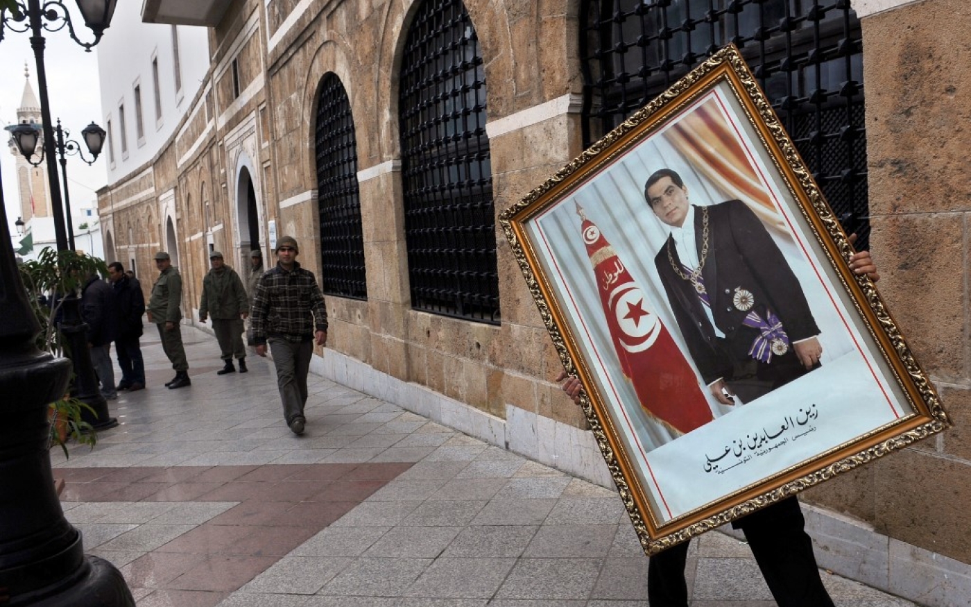 Un employé du Premier ministère retire un portrait du président déchu Zine el-Abidine Ben Ali, le 17 janvier 2011 (AFP)