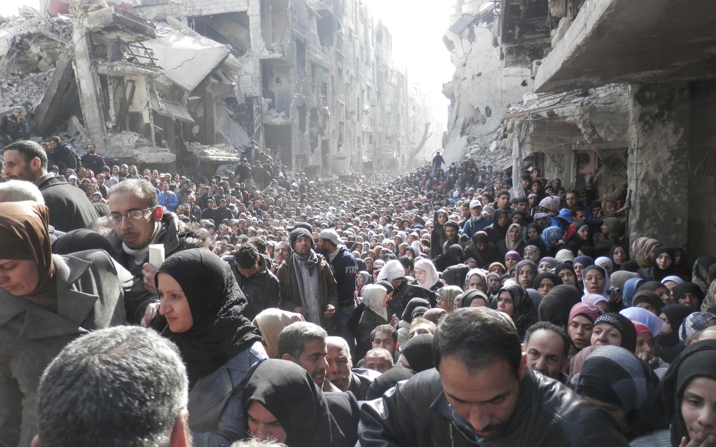 Des habitants attendent l’aide alimentaire distribuée par l’UNRWA dans le camp assiégé de Yarmouk, au sud de Damas, en 2014 (Reuters)