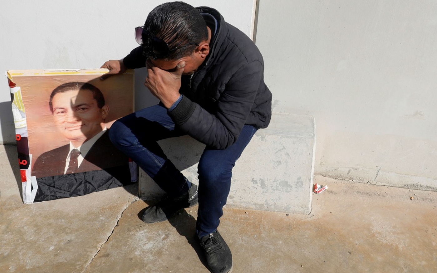Un partisan de l’ancien président égyptien Hosni Moubarak pleure en tenant une photo de lui devant la porte principale de la mosquée Tantawi, où se tiendront ses funérailles (Reuters)