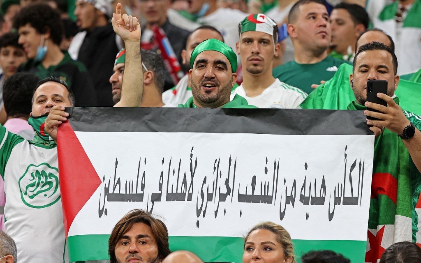 Des supporters algériens brandissent le drapeau palestinien comportant le message « le trophée est un cadeau du peuple algérien pour notre famille en Palestine » lors de la finale de la Coupe arabe de la FIFA, le 18 décembre 2021 (AFP)