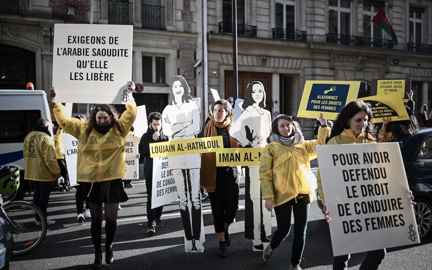 Des manifestantes tiennent des pancartes et des découpages de caricatures de femmes incarcérées en Arabie saoudite, devant l’ambassade d’Arabie saoudite à Paris, le 8 mars 2019 (AFP)