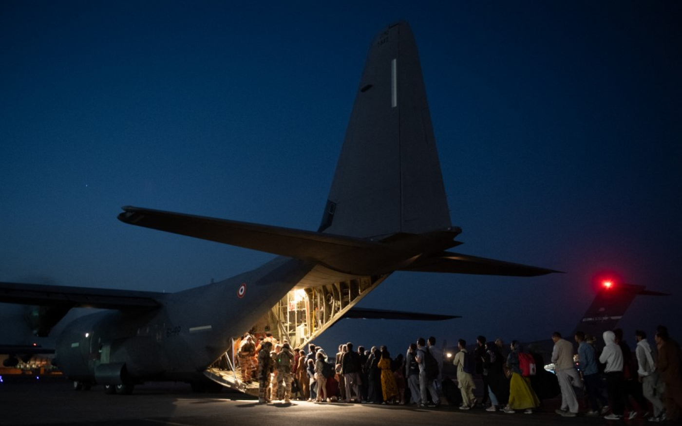 Des personnes embarquent à bord d’un avion militaire français à l’aéroport de Kaboul, destination Abou Dabi puis Paris, dans le cadre de l’opération Apagan, le 26 août 2021 (AFP)
