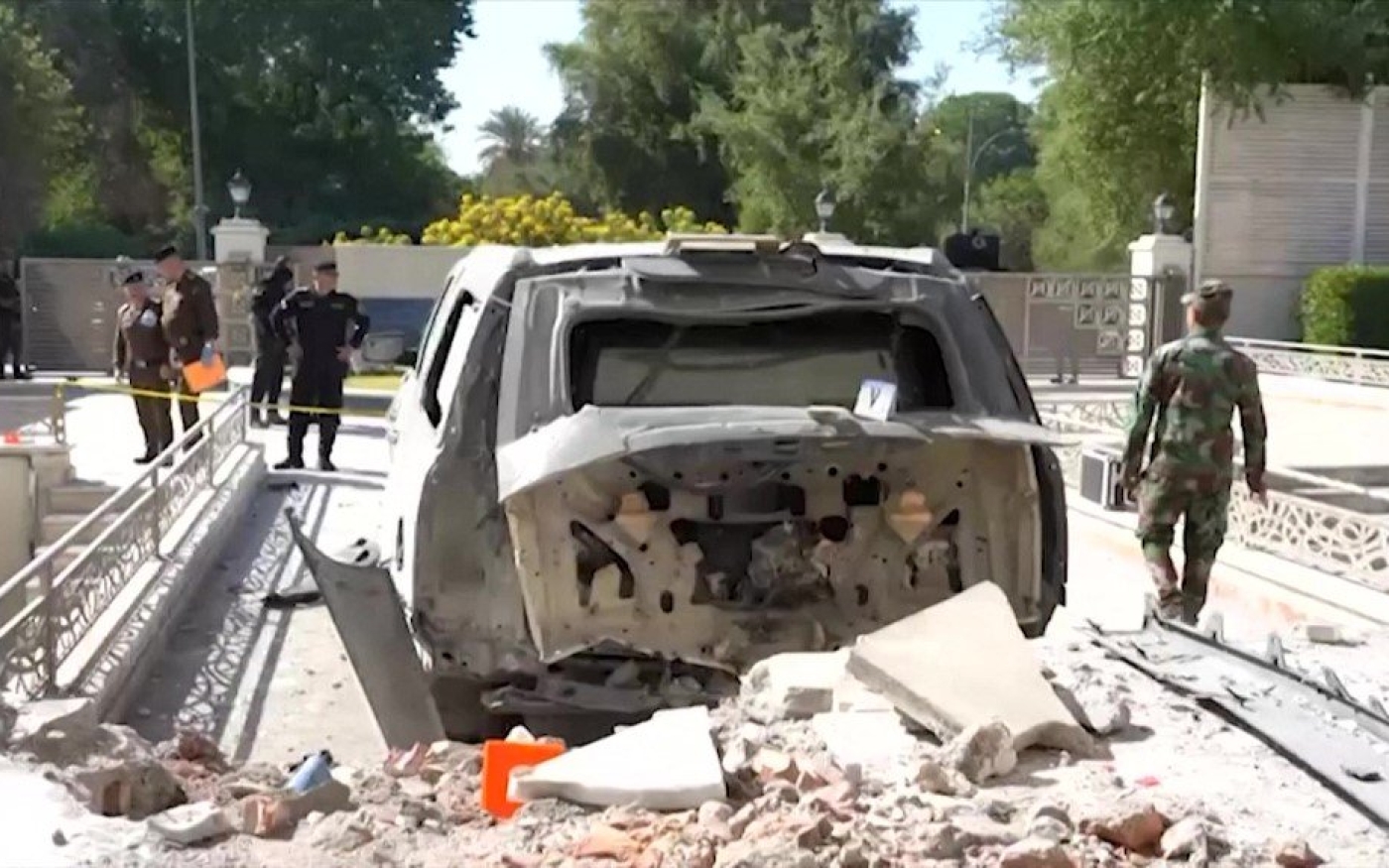 Des membres des forces de sécurité se trouvent près d’un véhicule endommagé après une frappe de drone contre la résidence du Premier ministre irakien à Bagdad, le 7 novembre 2021 (AFP)