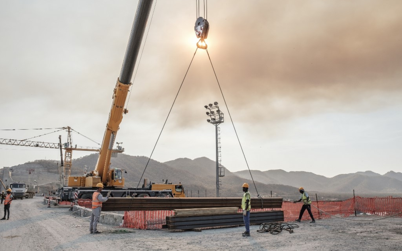 Des ouvriers déplacent des poutres en fer à l’aide d’une grue sur le chantier du barrage, le 26 décembre (AFP)