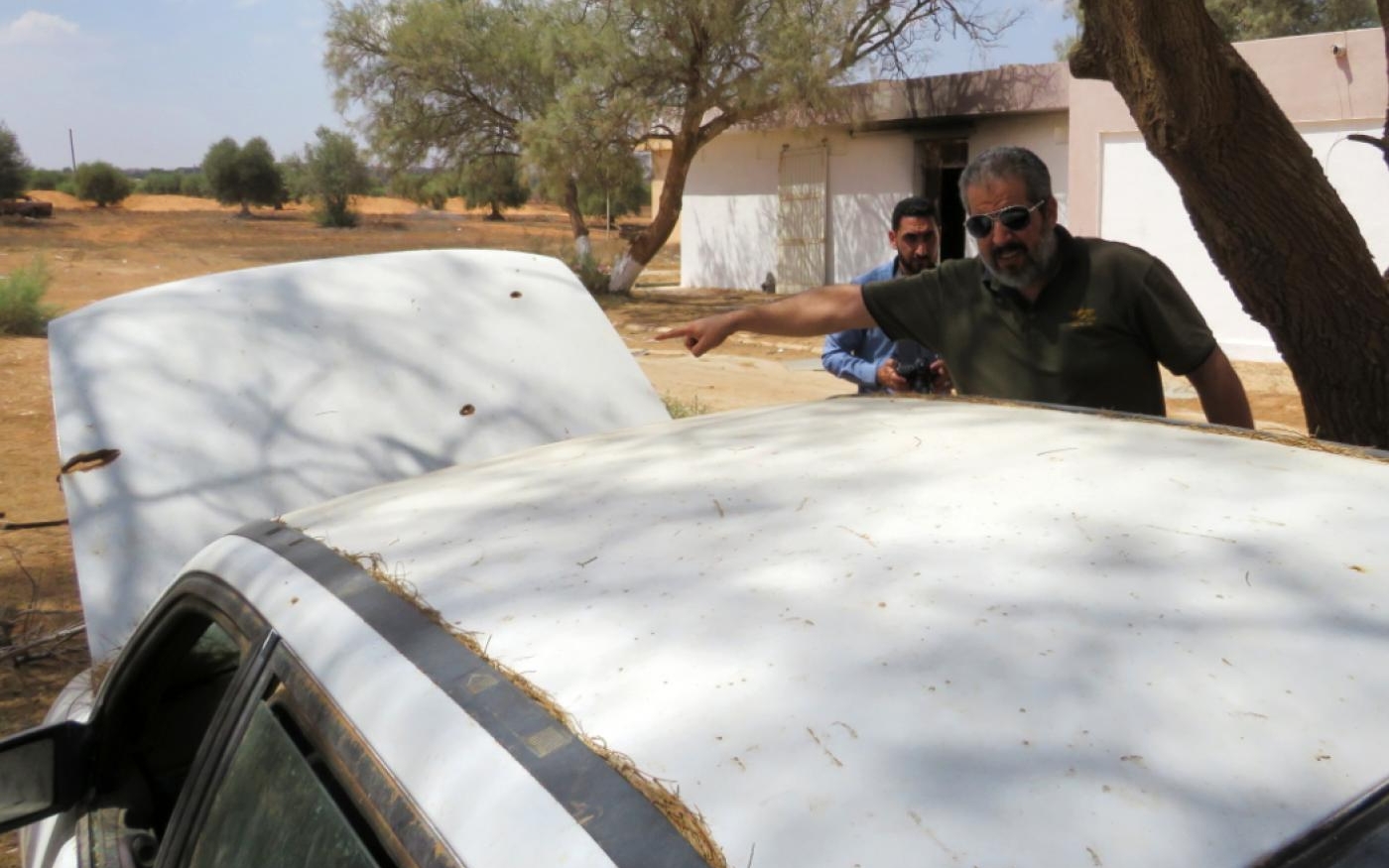 Le maire de Tarhouna, Mohammed Ali al-Kosher, montre des impacts de balles sur une voiture abandonnée (MEE/Daniel Hilton)