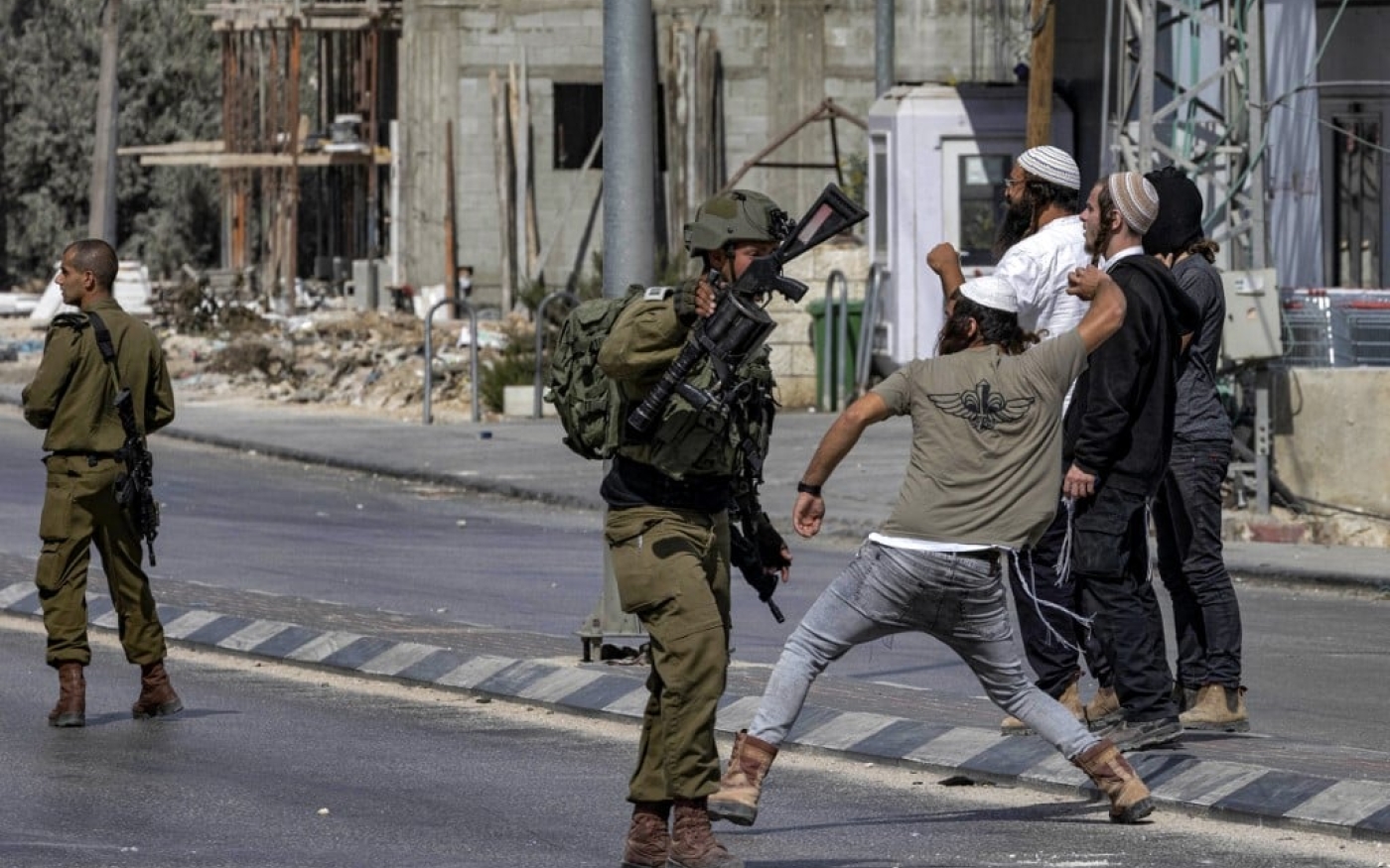 Des soldats israéliens protègent des colons israéliens qui jettent des pierres en direction de Palestiniens (non visibles sur la photo) au cours d’affrontements dans la ville de Huwwara (Cisjordanie occupée), le 13 octobre 2022 (AFP)