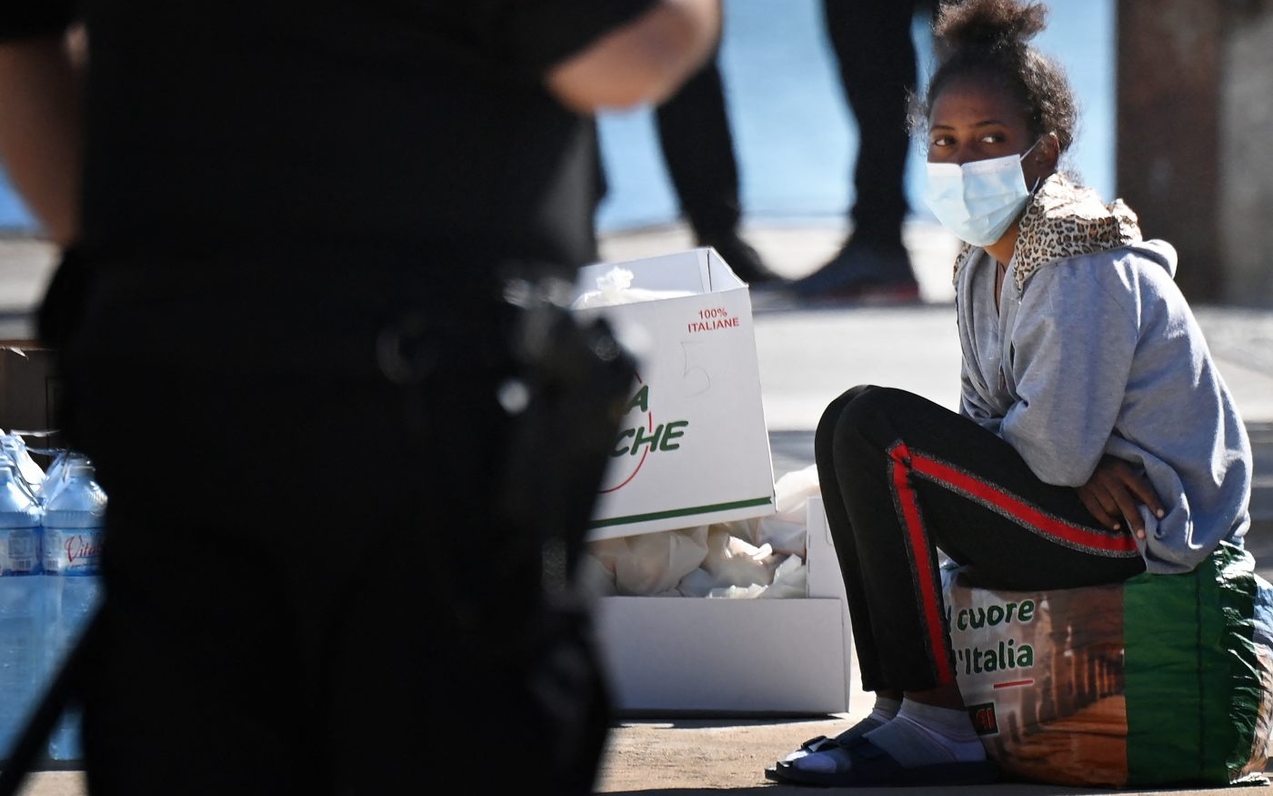 Sur l’île de Lampedusa, dans le sud de l’Italie, une jeune femme attend de monter à bord d’un ferry pour être transférée en Sicile puis dans les Pouilles, le 16 mai 2021 (AFP)