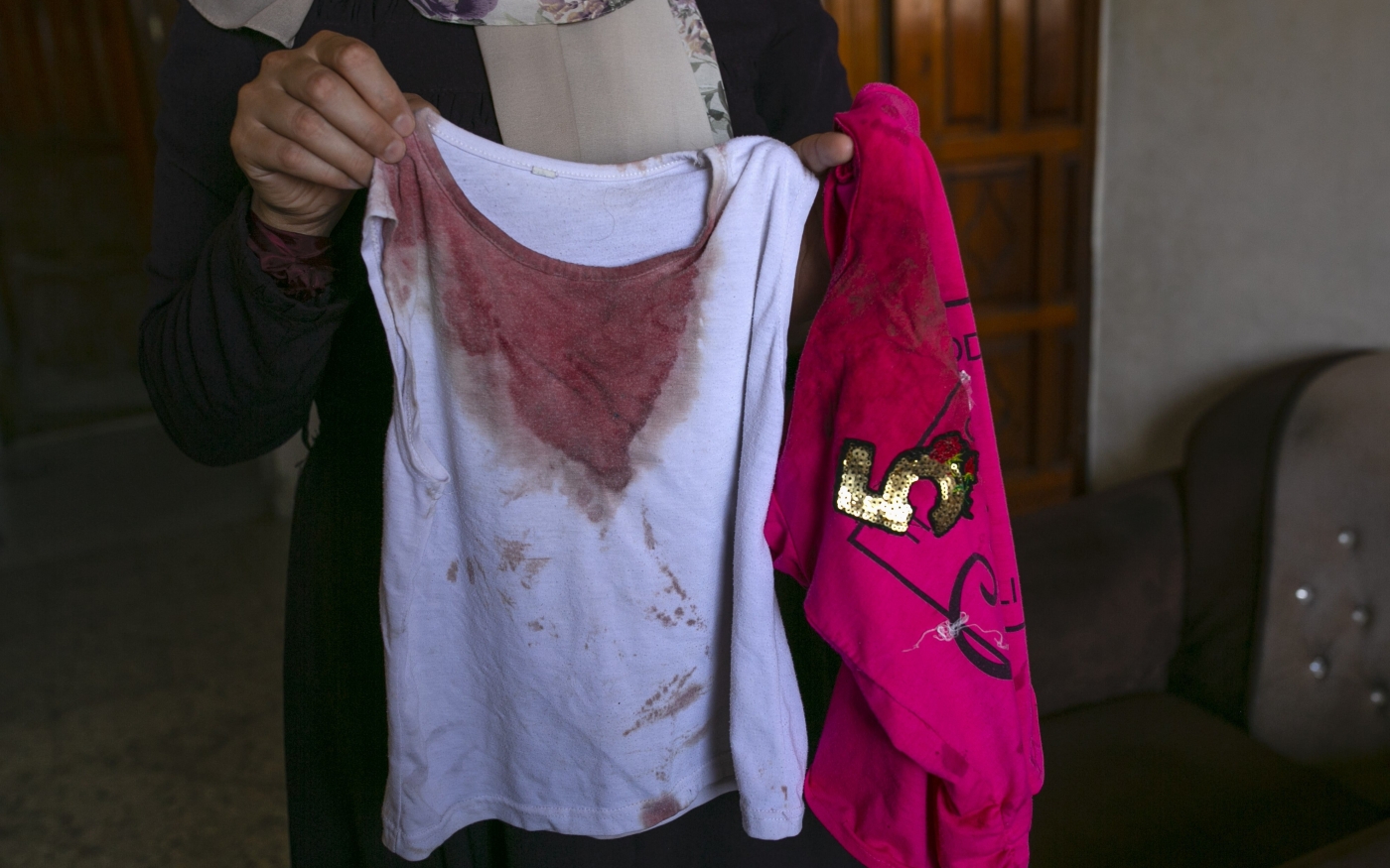 Une tante d’Alaa Qaddoum, fillette de 5 ans tuée par une frappe aérienne israélienne le 5 août 2022, montre son t-shirt tâché de sang (MEE/Samar Abu Elouf)