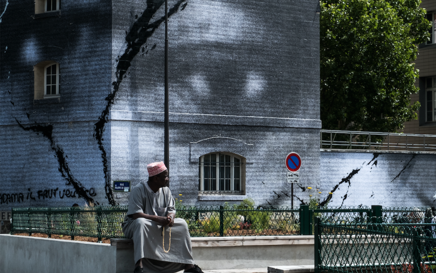 Un homme est assis près d’une fresque géante de l’artiste de rue français JR rendant hommage à Adama Traore, le 13 juin 2020 à Paris