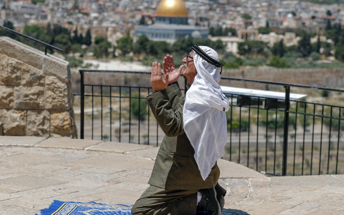 Un Palestinien prie au mont des Oliviers avec pour toile de fond la vieille ville de Jérusalem et l’enceinte de la mosquée al-Aqsa (AFP/Ahmad Gharabli)