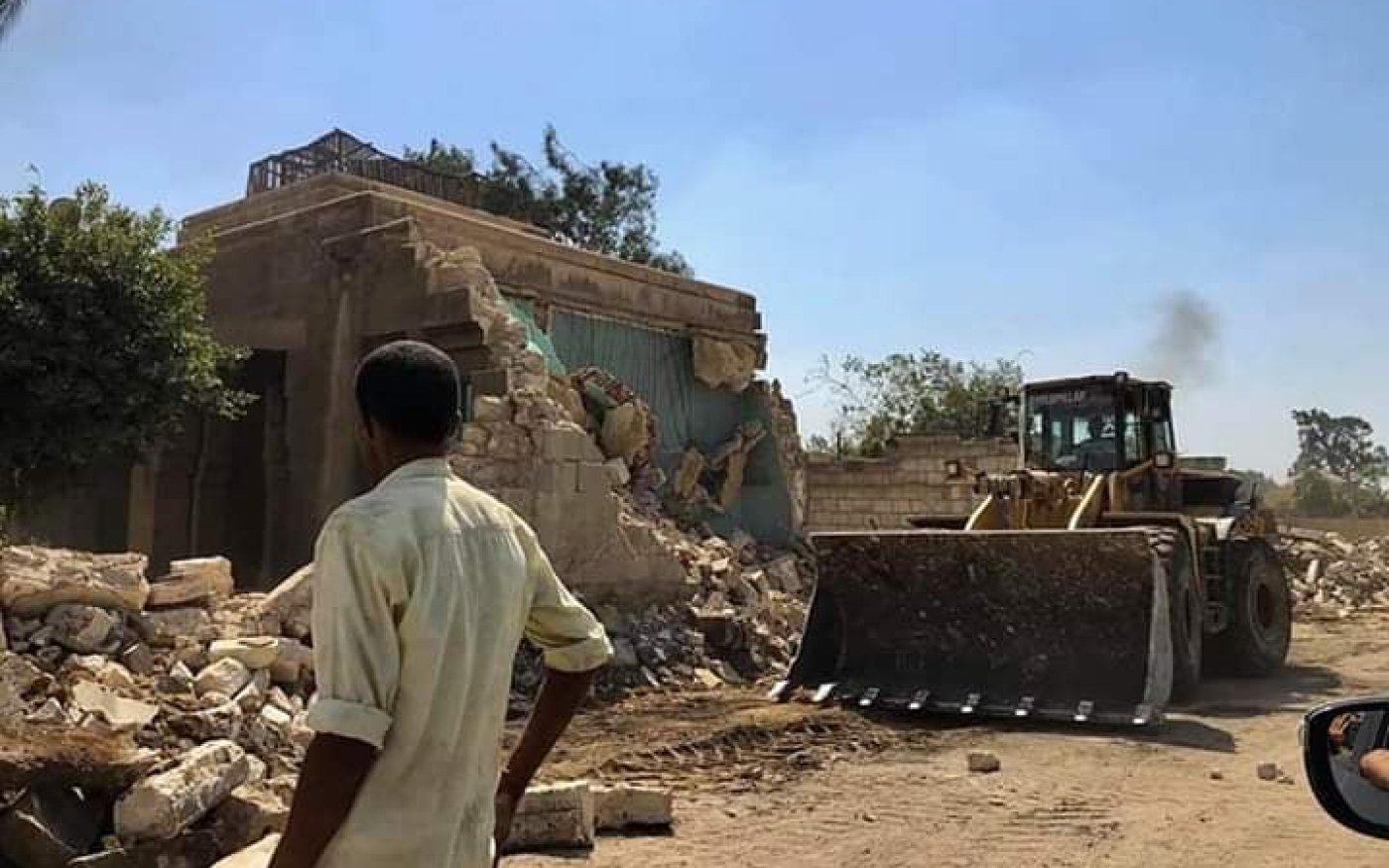Un démolisseur surveille un bulldozer qui rase des tombes de la Cité des morts, en juillet 2020 (MEE)