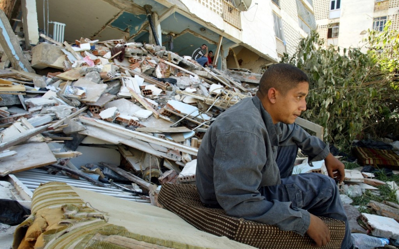 Un habitant de la Cité des 3 200 logements, le quartier le plus touché de Boumerdès, est assis près de son bâtiment détruit (AFP/Philippe Desmazes)
