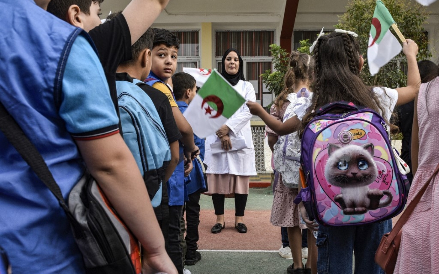 Le 19 septembre, jour de rentrée en Algérie, les enfants agitent le drapeau nationale dans la cour de l’école (AFP)