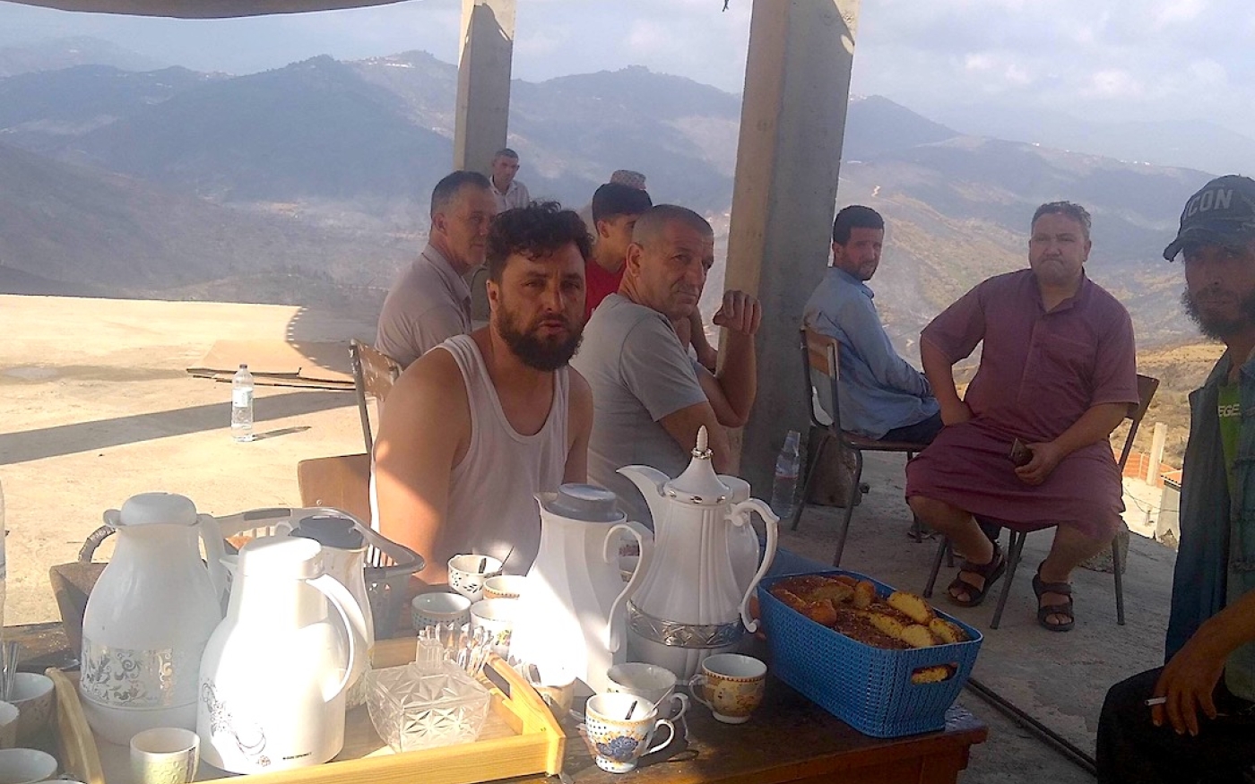 Sur les hauteurs du village, les habitants ont organisé un camp de fortune dans une maison inachevée pour revoir les visiteurs et les dons. Sur une table, sont posés des cafetières, des théières et des boîtes de gâteaux (MEE/Ali Boukhlef)
