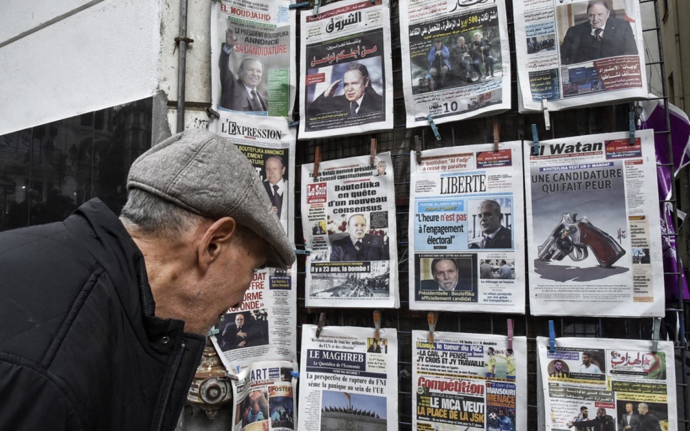 Un passant regarde les titres des quotidiens exposés dans la rue, au centre d’Alger (AFP/Ryad Kramdi)