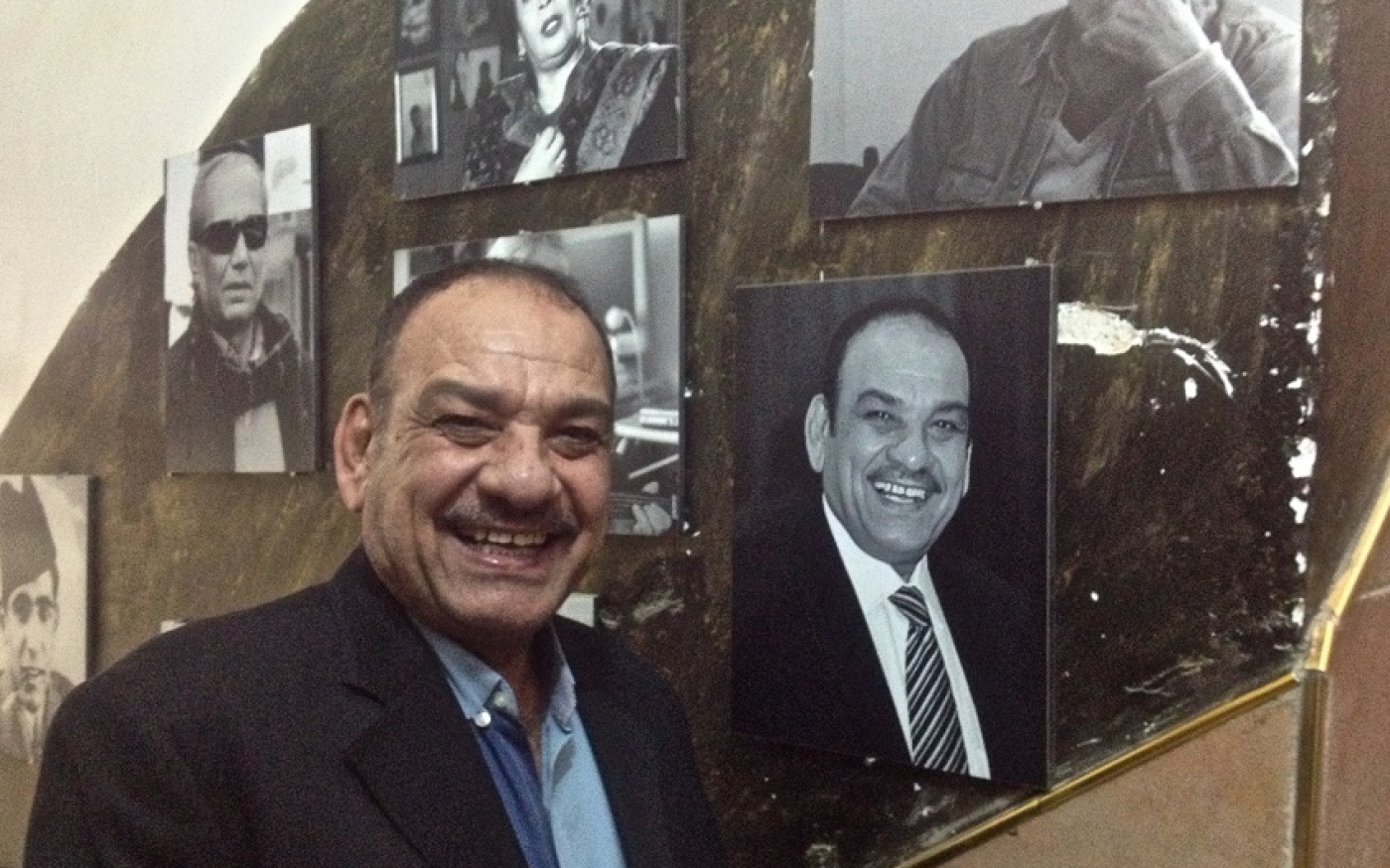 Le directeur de la troupe nationale de danse irakienne, Fouad Thanoon, se tient près de sa photo sur un « mur de la renommée » dans le quartier de Karrada à Bagdad (MEE/Tom Wescott)