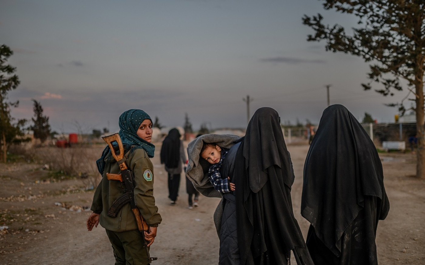 Des femmes soupçonnées d’appartenance à l’EI marchent sous la surveillance d’une combattante des FDS dans le camp d’al-Hol (Syrie), le 17 février 2019 (AFP)