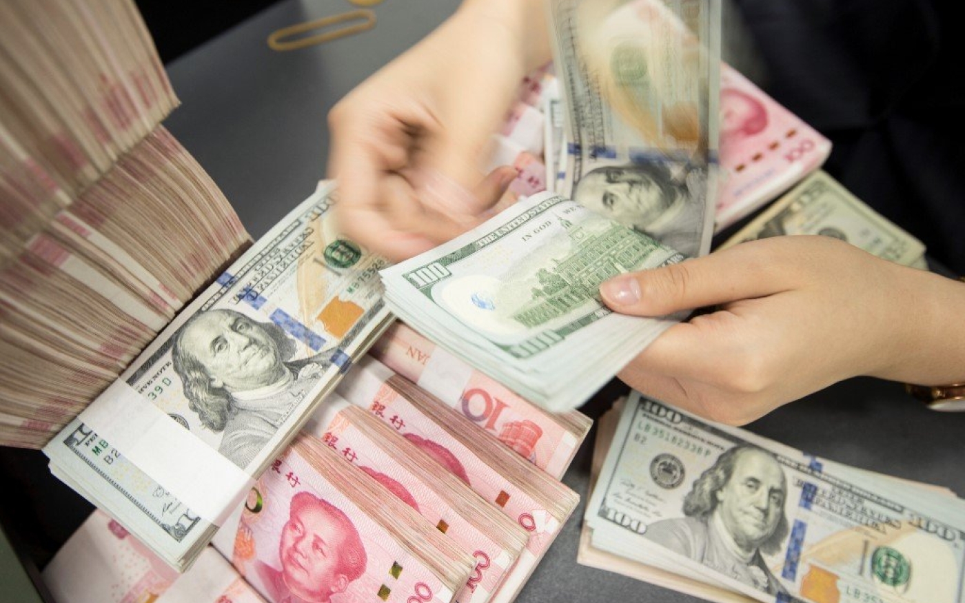 Une employée de banque chinoise compte des billets en yuans et dollars américains dans le Jiangsu en 2019 (AFP)