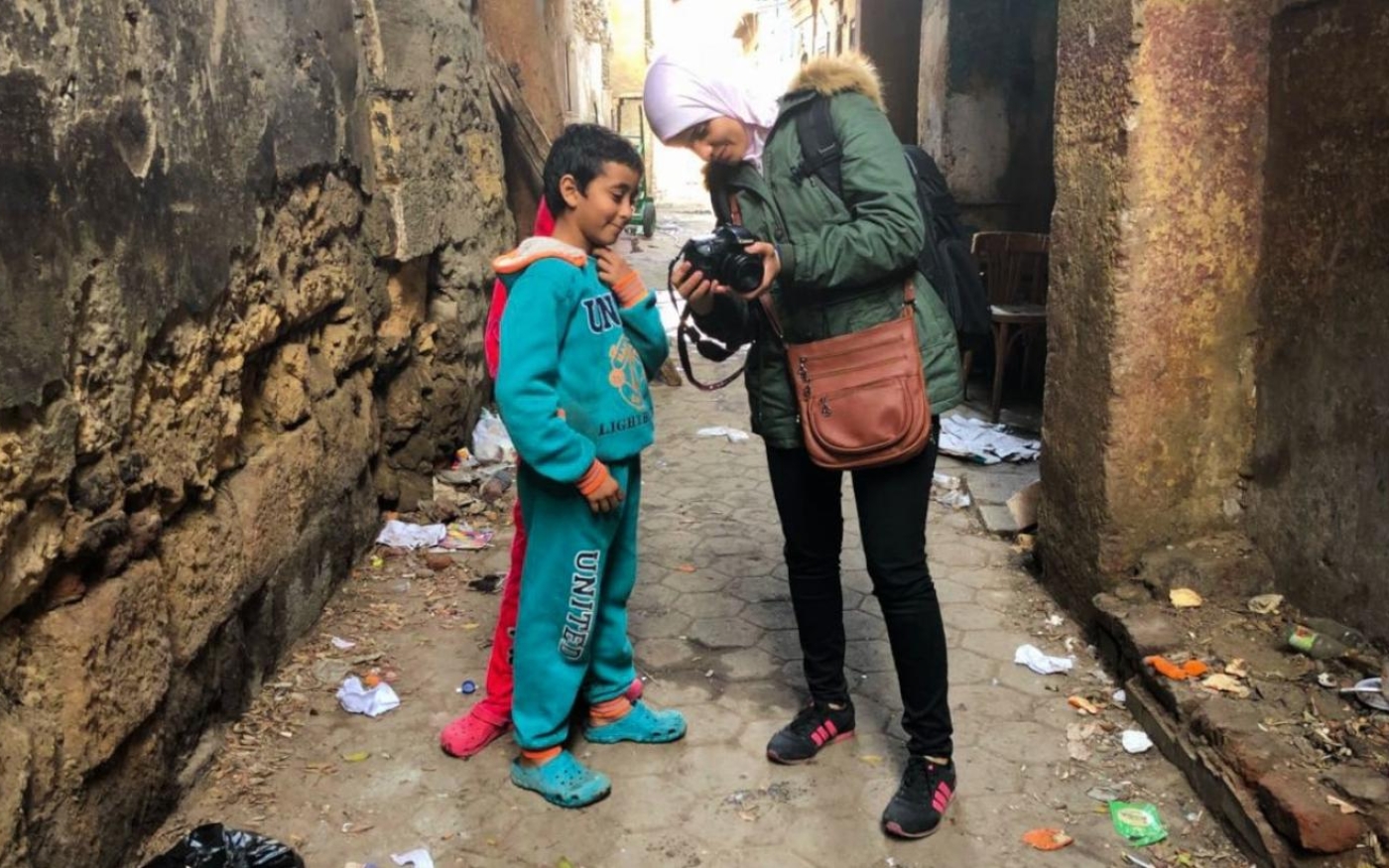La photojournaliste Somaya Abdelrahman montre son appareil photo à un écolier dans les ruelles du Caire, en février 2018 (Somaya Abdelrahman)