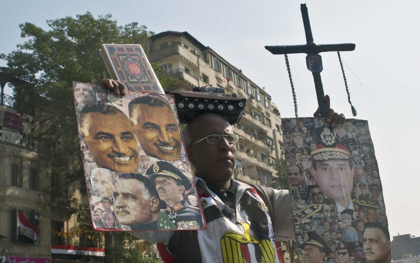 Un Égyptien tient des affiches, l’une représentant Abdel Fattah al-Sissi (à droite) et Sadate et Nasser (à gauche), le 6 octobre 2013 (AFP)