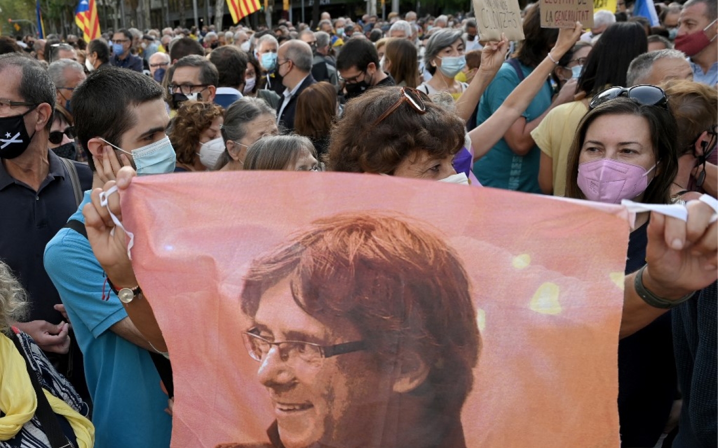 Un manifestant tient un portrait de Carles Puigdemont lors d’une manifestation devant le consulat italien à Barcelone le 24 septembre 2021 après l’arrestation en Italie de l’ancien président catalan exilé (AFP/Lluis Gene)