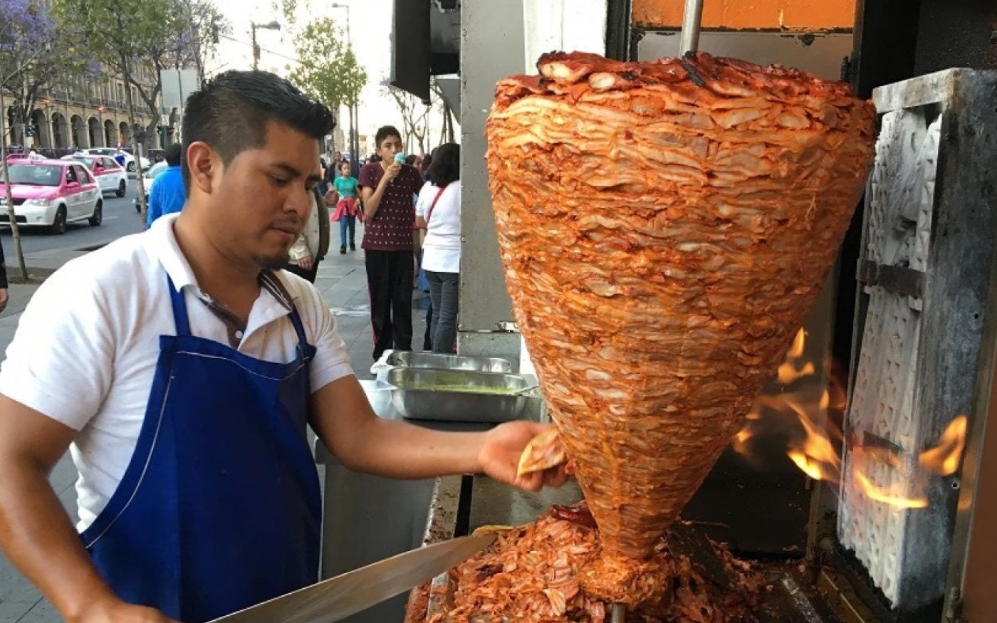 Un vendeur à Mexico découpe de la viande pour préparer des tacos al pastor, un plat probablement dérivé du chawarma, introduit par les immigrés libanais au début du XXe siècle (MEE/Alex Shams)
