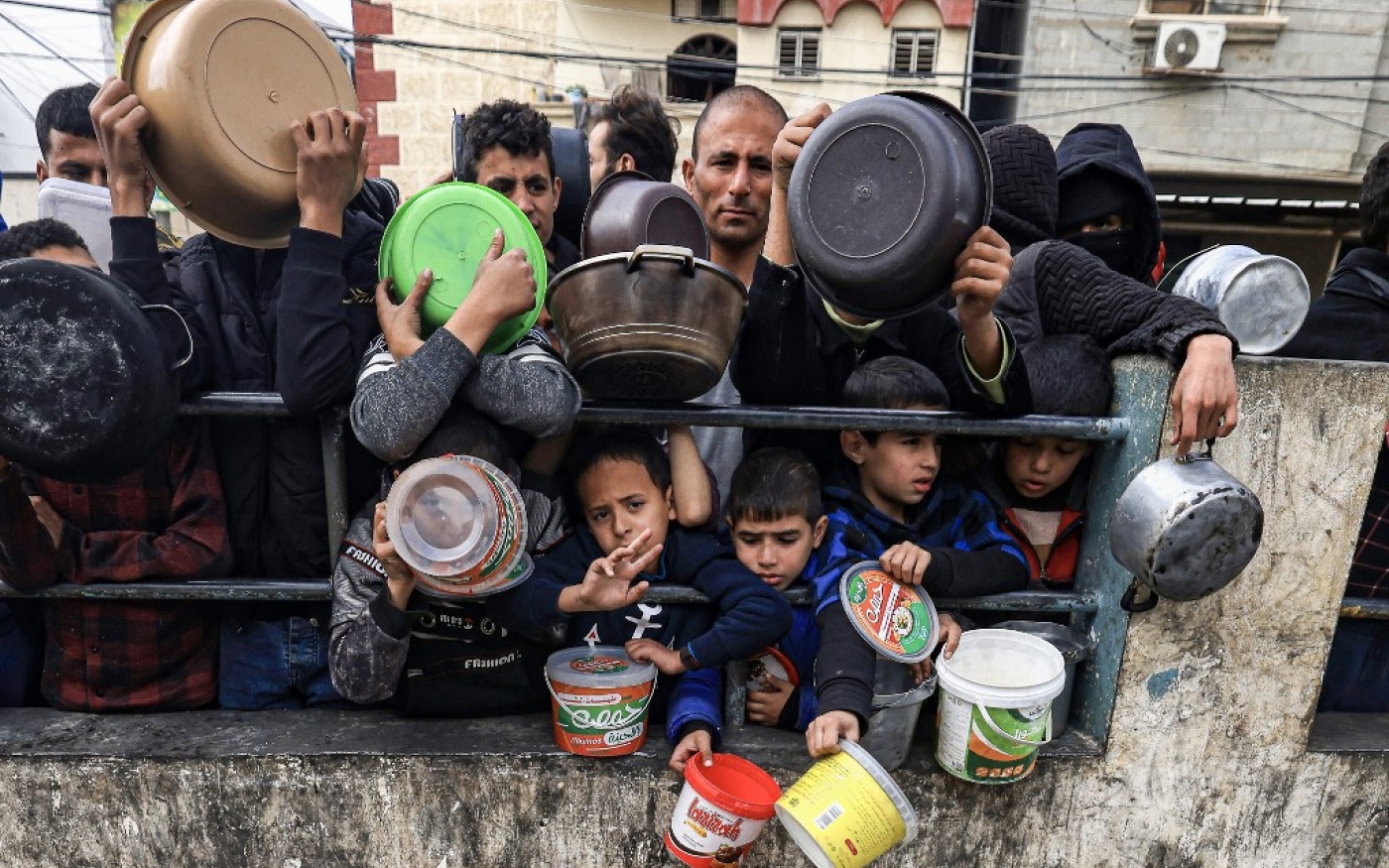 Des Palestiniens attendent de collecter de la nourriture à un point de don dans un camp de réfugiés à Rafah, dans le sud de la bande de Gaza, le 23 décembre 2023, au milieu des combats continus entre Israël et le groupe militant Hamas (AFP/Mahmud Hams)