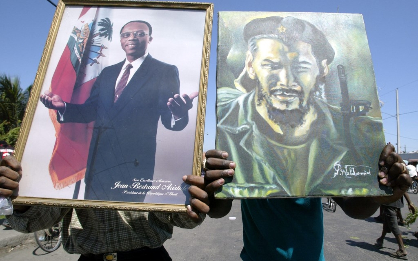 Deux partisans pro-Jean-Bertrand Aristide lors d’un rassemblement au centre-ville de Port-au-Prince le 5 mars 2004, alors qu’Aristide a fui le pays sous la pression d’un mouvement rebelle armé et de la communauté internationale. (AFP/Yuri Cortez)