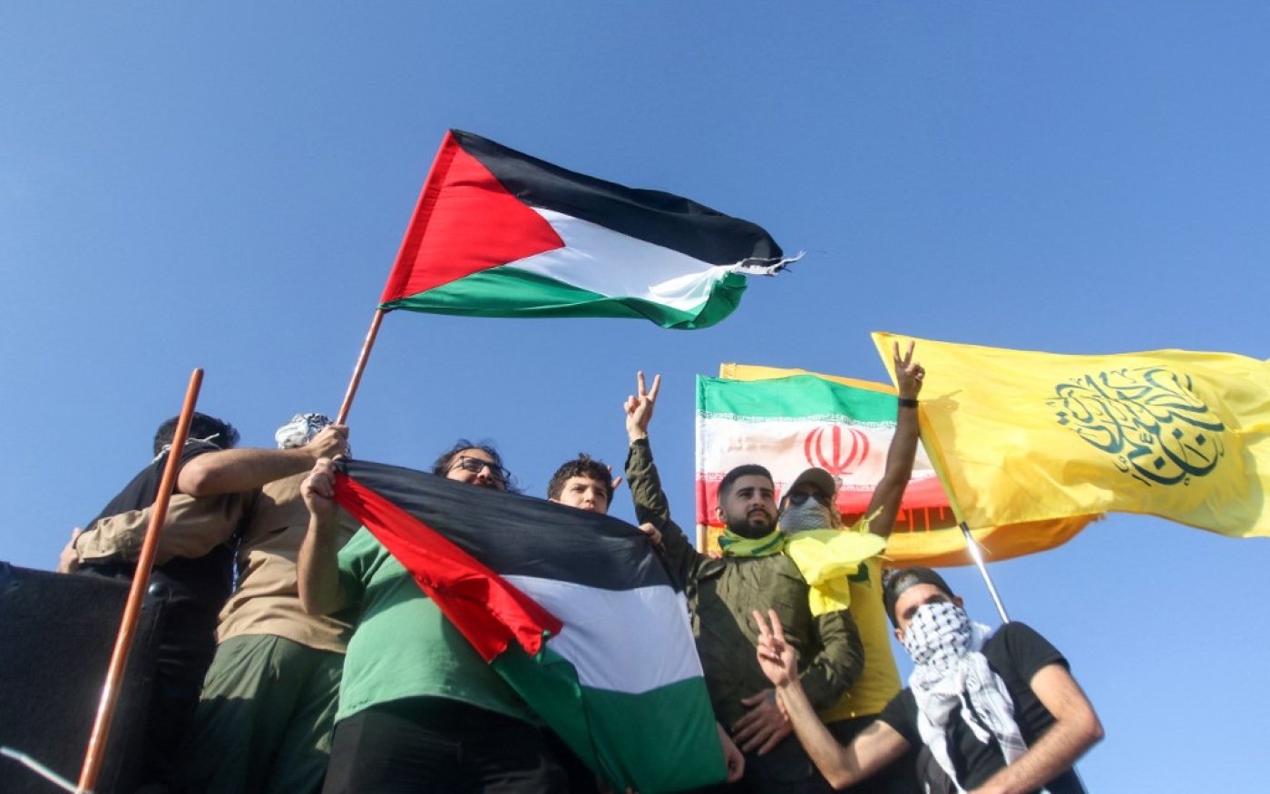 Des partisans du Hezbollah agitent les drapeaux de la Palestine et de l’Iran lors d’une manifestation anti-israélienne près de la frontière avec Israël, le 14 mai 2021 (AFP/Anwar Amro)