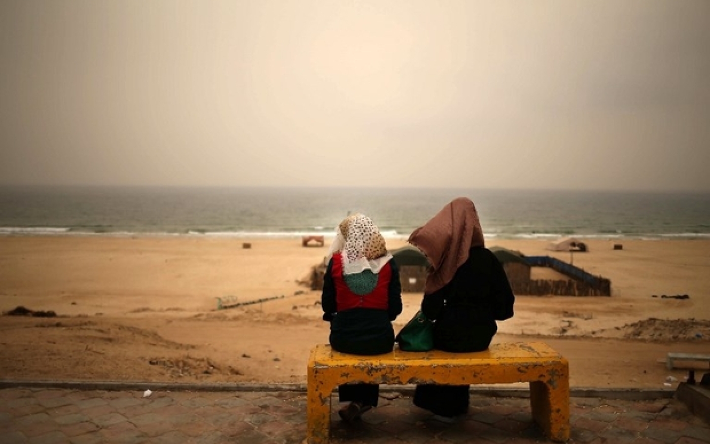 De jeunes Palestiniennes sont assises sur un banc de Gaza alors qu’une tempête de sable s’abat sur la ville, en septembre 2015 (AFP)