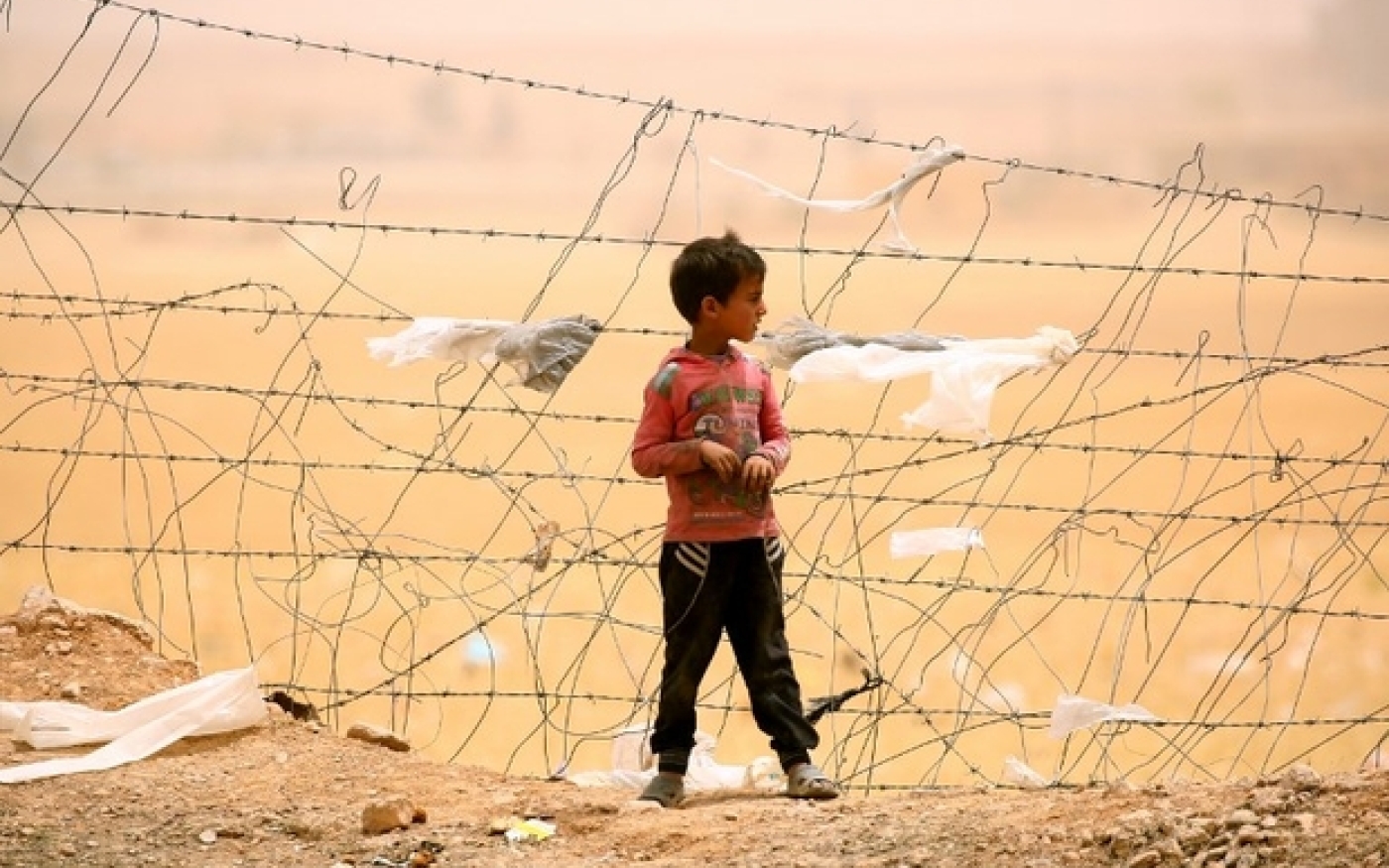 Un garçon syrien déplacé qui a fui le groupe EI à Raqqa se trouve près d’une clôture au cours d’une tempête de sable dans un camp temporaire dans le village d’Aïn Issa, dans le nord de la Syrie (AFP)