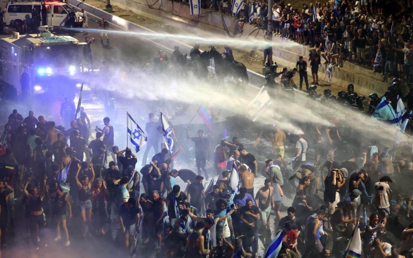 Les opposants au projet de réforme judiciaire manifestent sous les canons à eau des forces de sécurité qui cherchent à les déloger, à Jérusalem, le 24 juillet 2023 (AFP/Jack Guez)