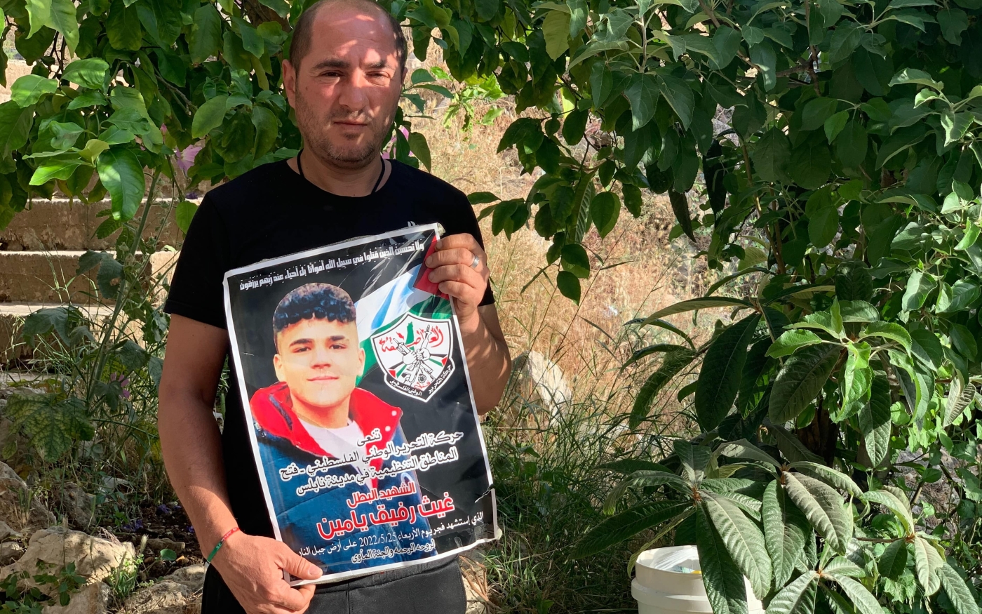 Rafiq Yamin tient une affiche montrant son fils décédé, Laith (16 ans), à son domicile de Naplouse, en Cisjordanie occupée (MEE/ Shatha Hammad)