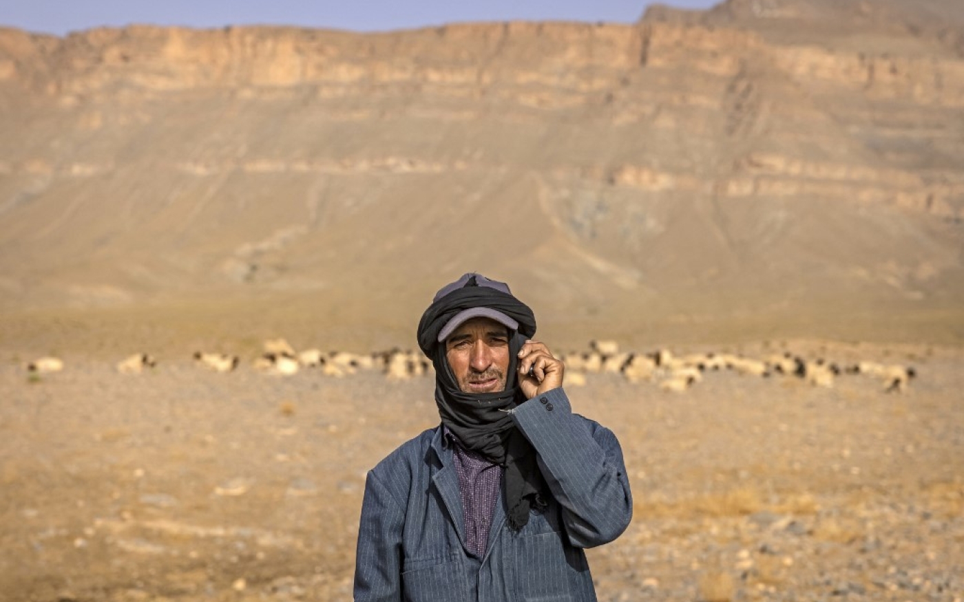 Un Amazigh pose à côté d’un troupeau de moutons près du village d’Amellagou où résident les derniers nomades du Maroc, le 2 septembre 2022. Les derniers nomades du pays affirment que leur ancien mode de vie est devenu impossible en raison du changement climatique qui entraîne des sécheresses de plus en plus intenses (AFP/Fadel Senna)