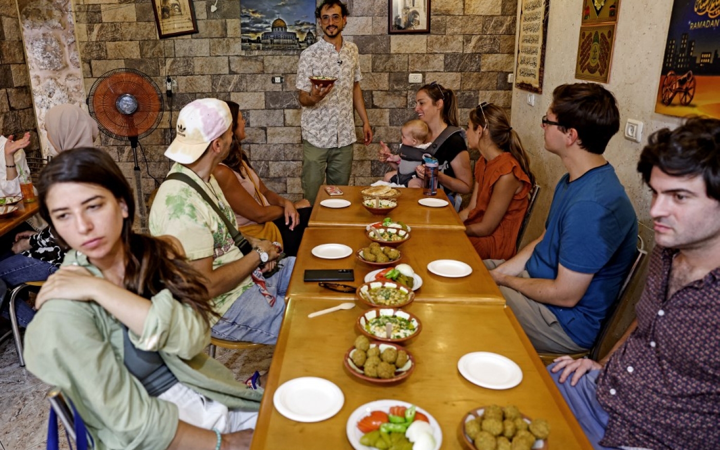 Le guide touristique Izzeldin Bukhari présente des plats aux touristes dans un restaurant lors d’une visite guidée dans la vieille ville de Jérusalem le 26 juillet 2022 (AFP/Ahmad Gharabli)