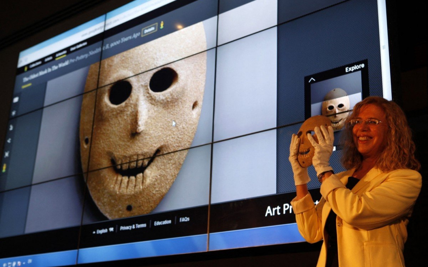 La conservatrice du Musée d’Israël, Debby Hershman, brandit un masque néolithique, également projeté en arrière-plan, dans le cadre du Google Art Project en avril 2012, à Jérusalem (AFP)